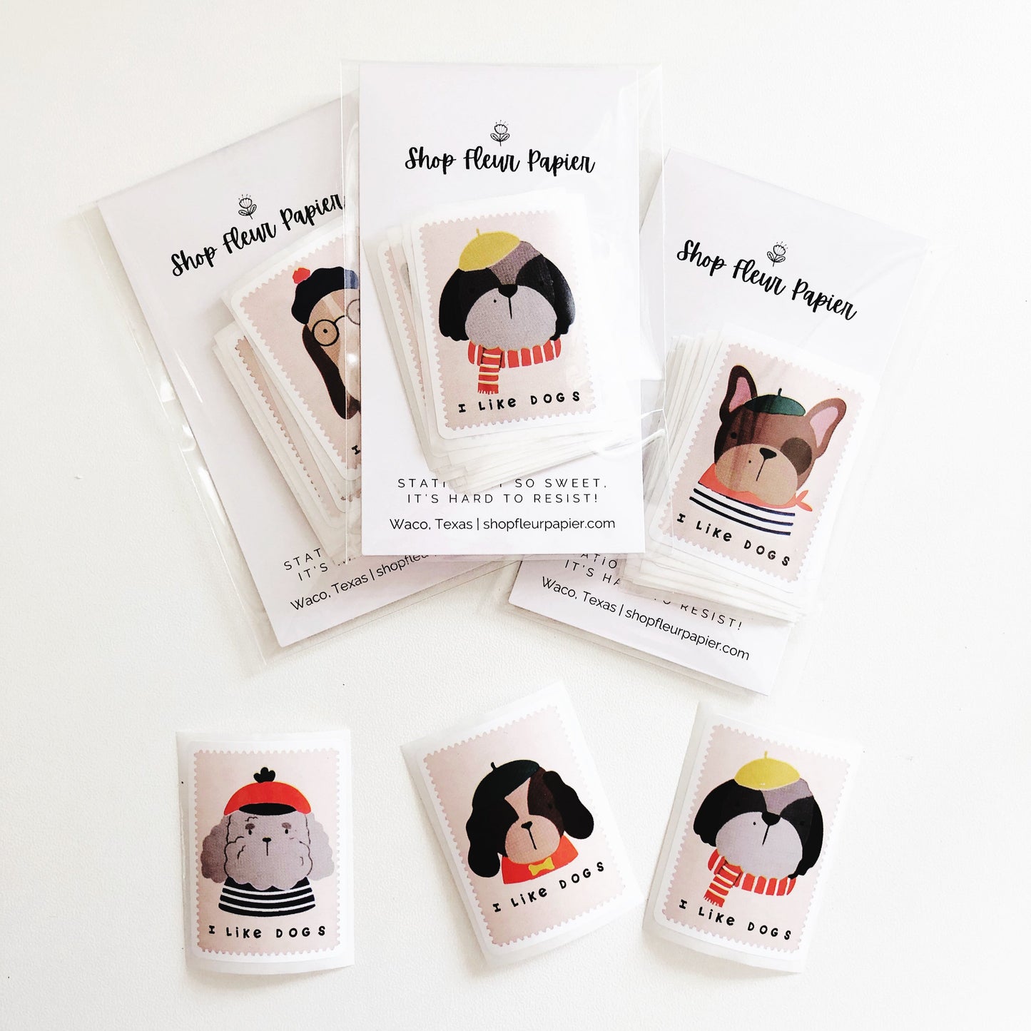 A photo showing multiple sheets of dog stickers from Shop Fleur Papier. Each sheet features a different dog breed with the phrase 'I Like Dogs' and the Shop Fleur Papier logo.
