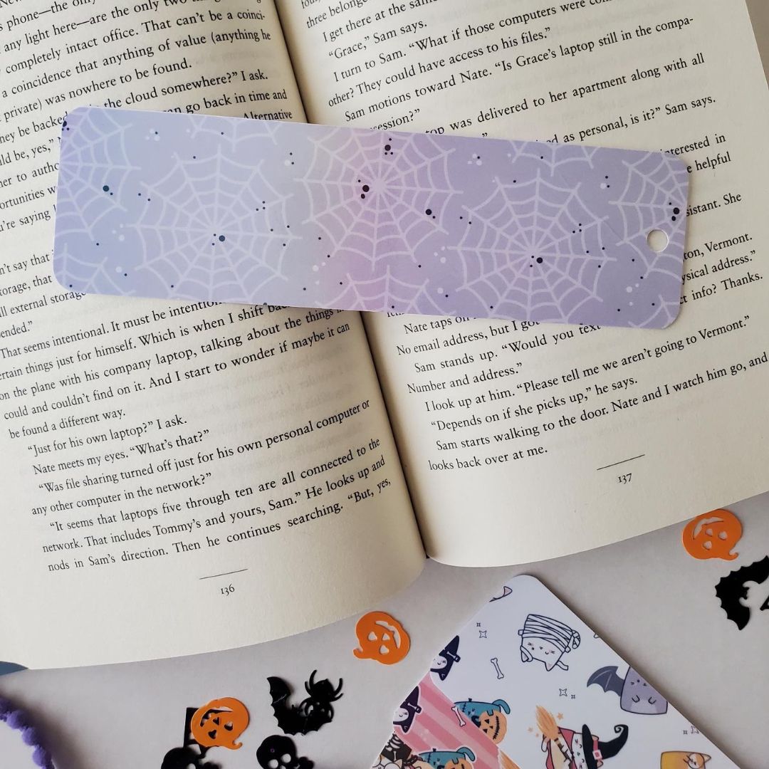 Bookmark with a pale purple spiderweb design featuring scattered black specks and rounded edges