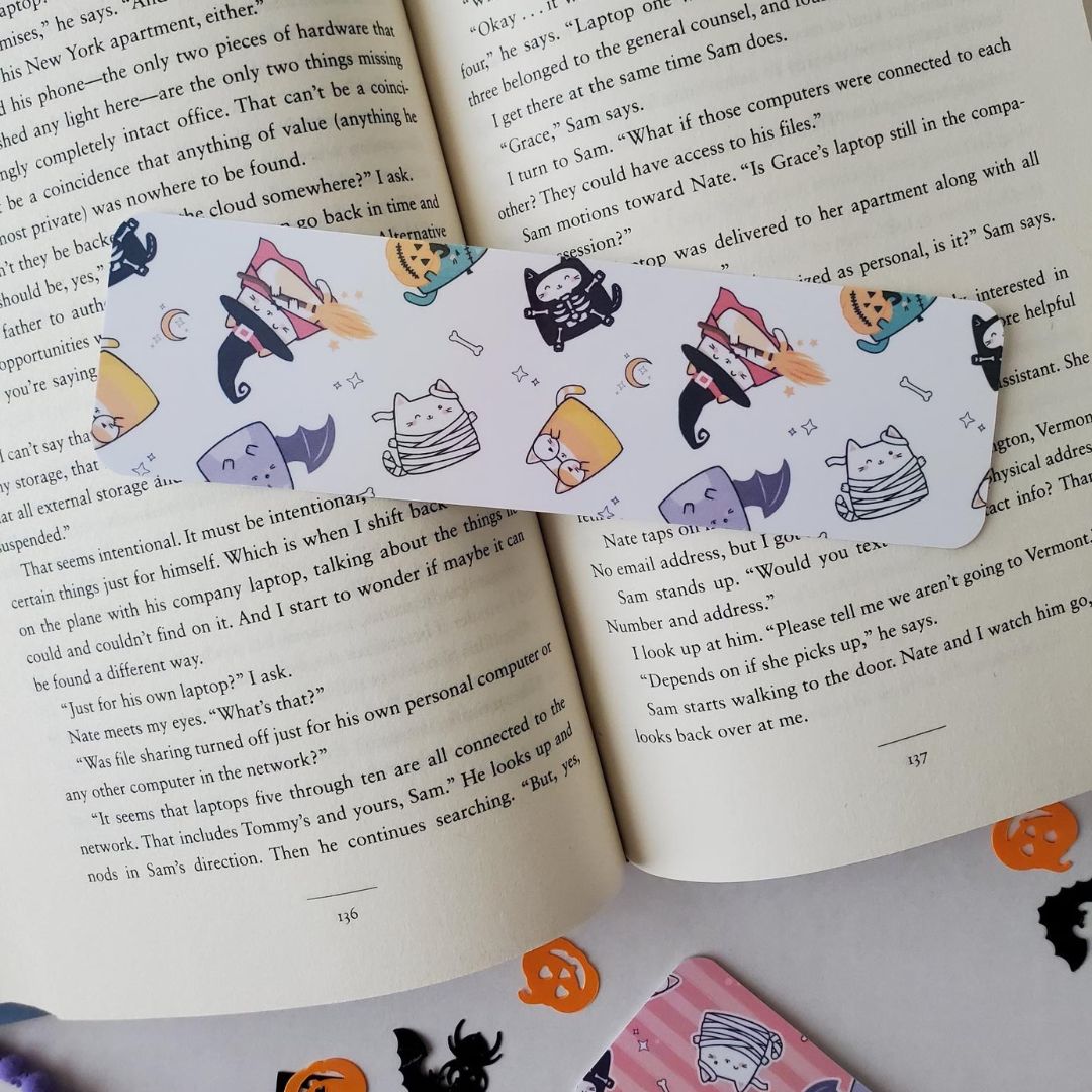 Halloween bookmark with a white background and playful cats dressed as witches flying on broomsticks.